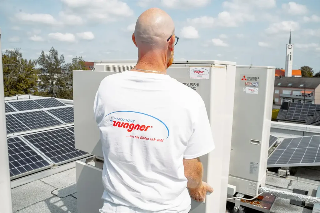 Techniker in Firmenkleidung wartet Klimaanlage auf einem Dach mit Solarpanelen, symbolisiert nachhaltige Energie