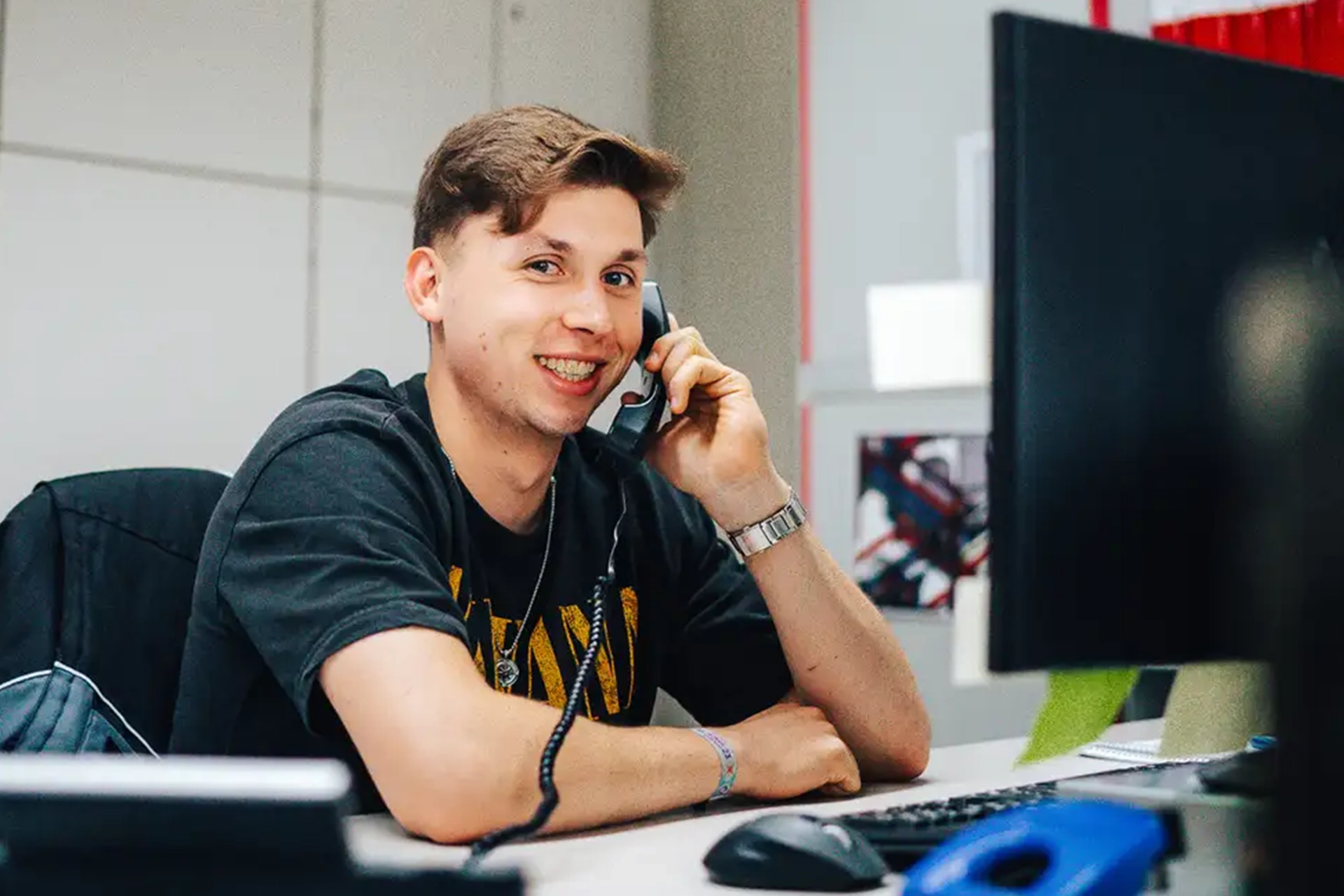 Junger Mann am Telefon in einem Büro, der Praktika, Ausbildung und Studium darstellt