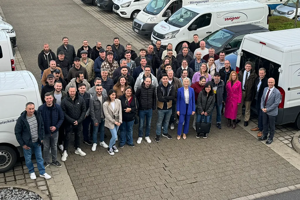 Gruppenfoto eines Teams vor Firmenfahrzeugen zur Darstellung des Gemeinschaftsgefühls