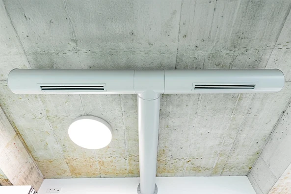 Moderne Lüftungsanlage mit schlankem, weißem Rohrsystem an einer Betondecke – effiziente Klimatisierung für Gewerbe- und Wohnräume.